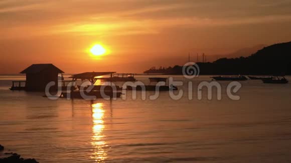 佩穆特兰湾的橙色日出巴厘岛小屋和水上船只视频的预览图