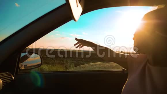 青少年在汽车慢动作视频中挥动她的手年轻快乐的小女孩开着一辆车手伸出来视频的预览图