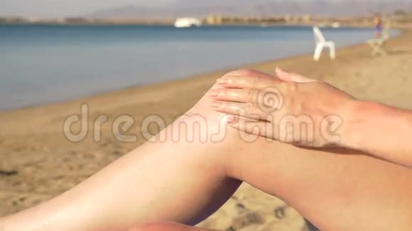美丽的年轻女子在海滩上涂防晒霜高清高清视频的预览图
