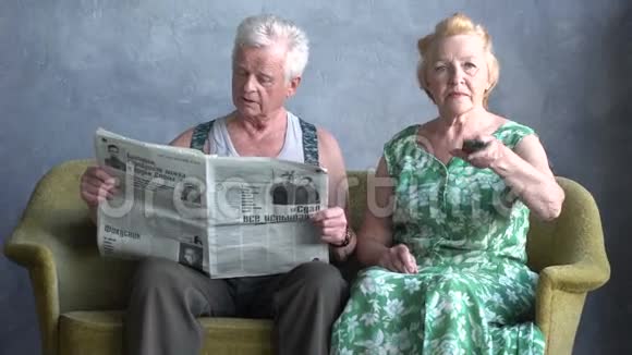 严肃的交谈老年夫妇妻子在看电视丈夫在看报纸视频的预览图
