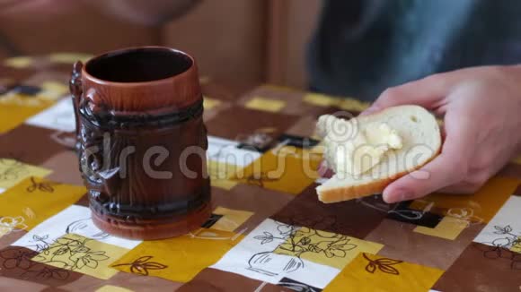男人正在一杯热咖啡旁边的面包上抹黄油视频的预览图