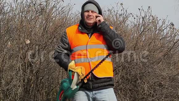 景观工人与灌木切割机谈手机视频的预览图