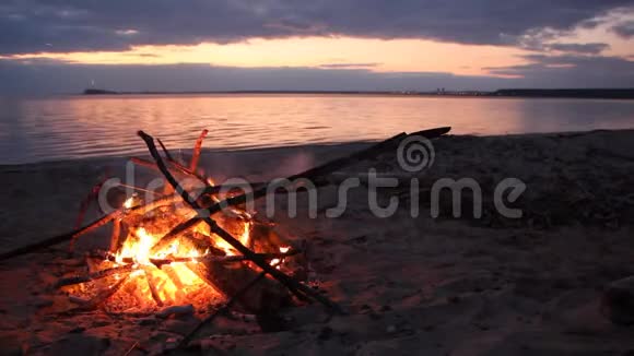 日落时河岸上熊熊燃烧的篝火视频的预览图