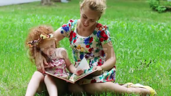 小女孩和她妈妈读了一本关于夏天公园草地的书视频的预览图