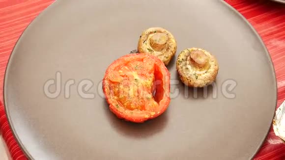 用锋利的不锈钢刀叉切烤番茄和蘑菇带有番茄和草菇的棕色圆形盘子视频的预览图