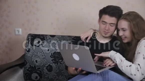 年轻夫妇在室内共用一台笔记本电脑视频的预览图