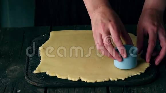 用女人的双手在旧木桌上做些小饼干上面印着家字的蓝色邮票视频的预览图
