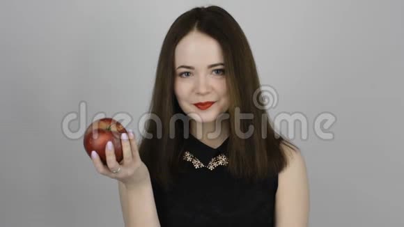 美丽的年轻女子吃红苹果微笑着视频的预览图