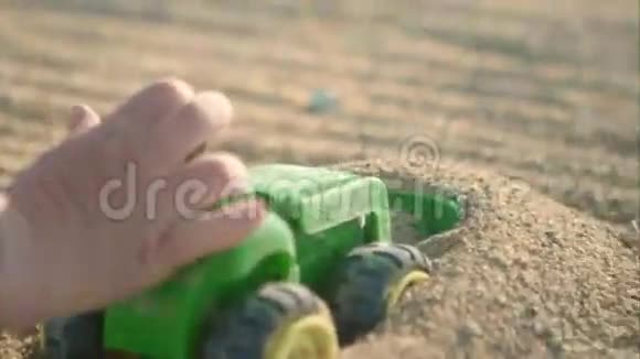 一辆玩具绿色卡车在沙滩上行驶视频的预览图