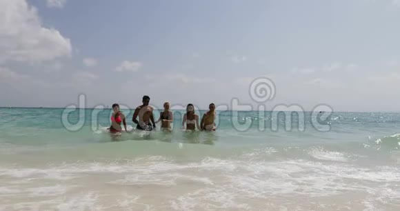 沙滩上的水上奔跑的人们夏日快乐的男女游客视频的预览图