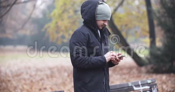 男子在秋季公园的长凳上发短信视频的预览图