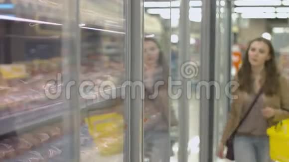 站在冰箱里放肉的货架旁边的年轻女子视频的预览图