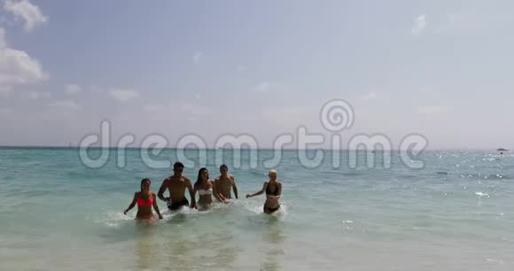 沙滩上的水上奔跑的人们夏日快乐的男女游客视频的预览图