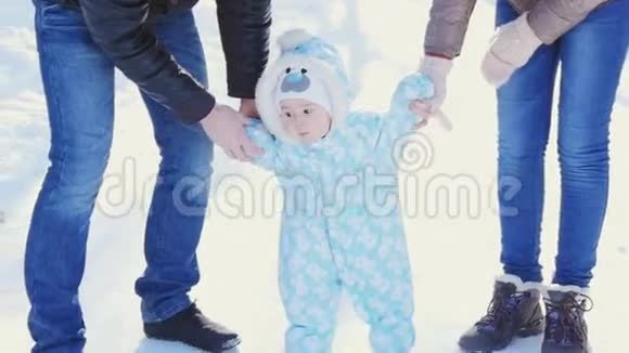 一个幸福的家庭爸爸妈妈教孩子在冬季公园散步视频的预览图