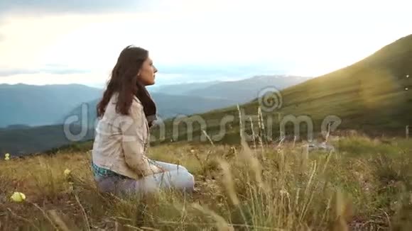 年轻女子坐在山上欣赏美丽的日落在福尔特文图拉的科菲德海岸线上俯瞰美景视频的预览图