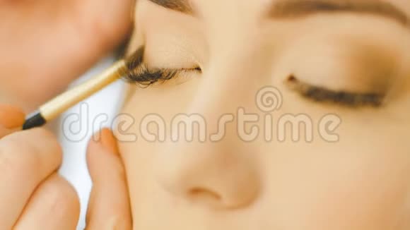 专业眼妆师应用眼影粉漂亮的女人脸完美的妆容美容时尚视频的预览图