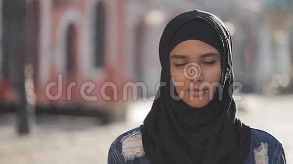 戴头巾的年轻美丽穆斯林女子的肖像注视着站在老城区的镜头视频的预览图