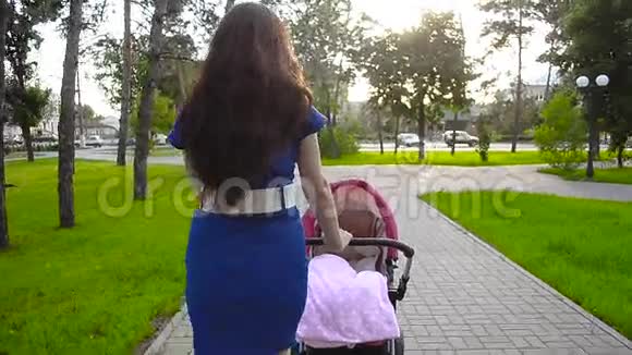 妈妈带着婴儿车散步暑假在公园里休息一天视频的预览图