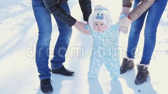 一个幸福的家庭爸爸妈妈教孩子在冬季公园散步视频的预览图
