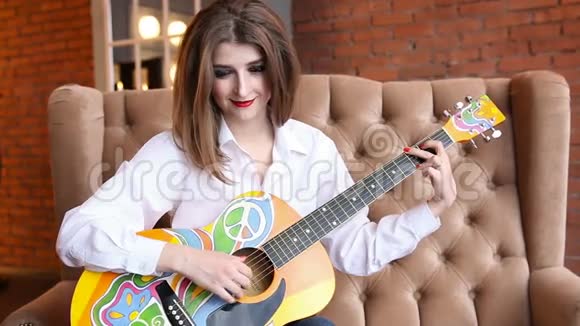 穿着白色衬衫的女孩用嬉皮风格弹吉他视频的预览图