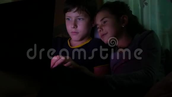 儿童男孩和女孩在儿童夜间上网游戏中玩笔记本电脑视频的预览图