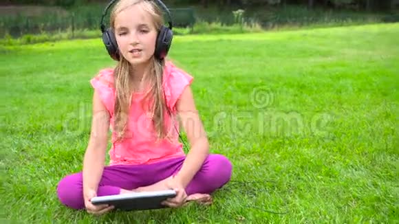 女孩在户外平板电脑上听音乐视频的预览图