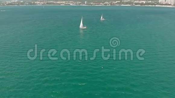 夏天一艘白色的游艇带着帆在蓝色的海里漂浮空中射击视频的预览图
