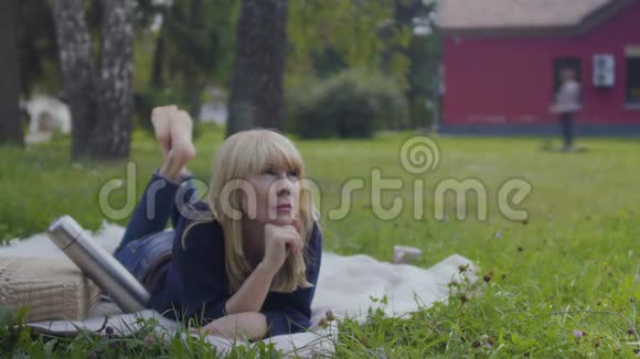 美丽的成年女人在公园的毯子上放松视频的预览图