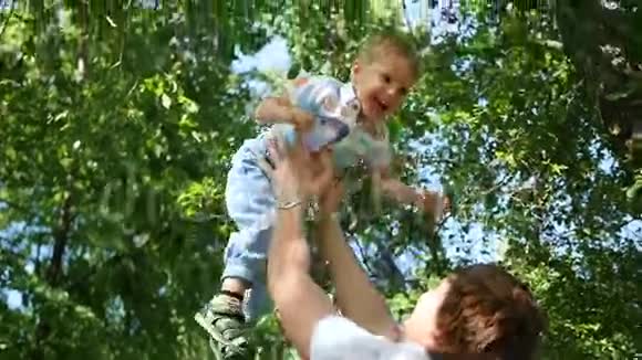 慢动作一位年轻的父亲把他那爱笑的婴儿抛向空中户外娱乐视频的预览图