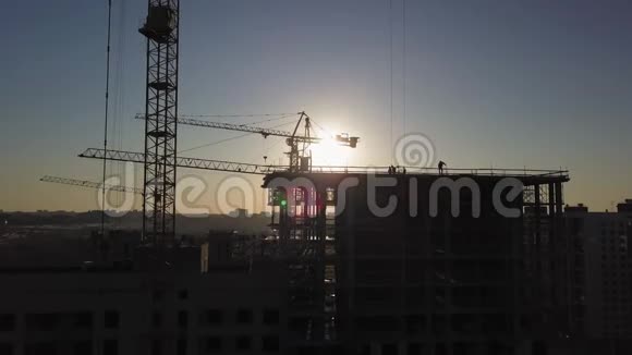 日落时施工现场建筑物附近建筑起重机的剪影视频的预览图