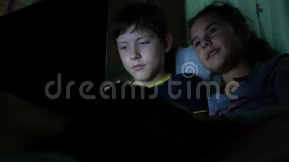 儿童男孩和女孩晚上在笔记本电脑上玩儿童在线游戏视频的预览图