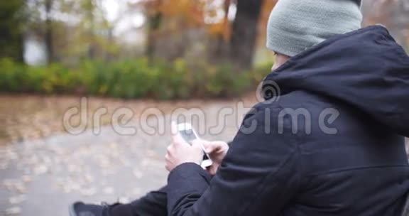 男子在秋季公园的长凳上发短信视频的预览图