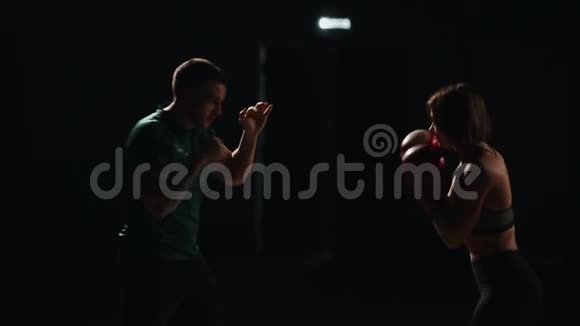 肌肉健身女孩训练与他的教练进行打击脚拳击手套自我的教训视频的预览图