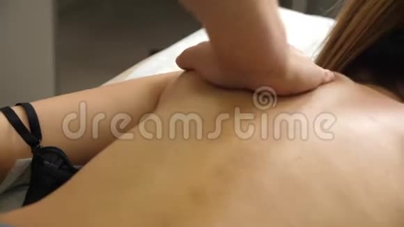 手动治疗师按摩躺在按摩台上的年轻女子推着背部男性按摩师的手按摩视频的预览图