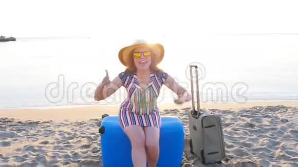 快乐的年轻女子在度假时提着一个手提箱竖起大拇指视频的预览图