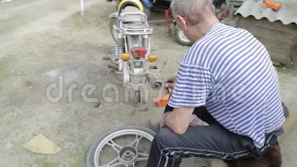 一位老人在村里的院子里修理摩托车视频的预览图