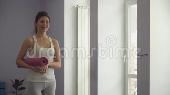 女孩站在瑜伽垫准备锻炼视频的预览图