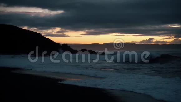 海滩上美丽的日落石头上的波浪视频的预览图
