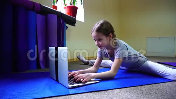 女孩坐在地板上的树枝位置并与朋友通过互联网在笔记本电脑上重写视频的预览图