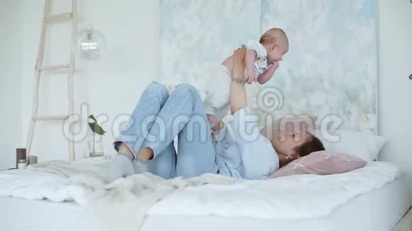 年轻可爱的女孩在床上和儿子玩视频的预览图