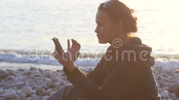 迷人的女人在日落时分使用智能手机视频的预览图