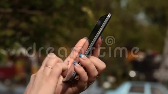 年轻女性在户外使用智能手机在智能手机上写信息视频的预览图