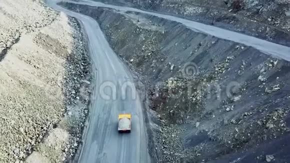 自卸卡车在采石场顶部的景观驾驶橙色自卸卡车与碎石在道路露天坑采矿重型运输视频的预览图