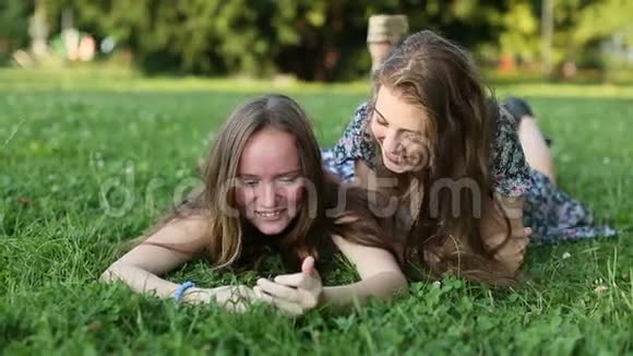 两个女孩躺在草坪上聊天玩得很开心视频的预览图