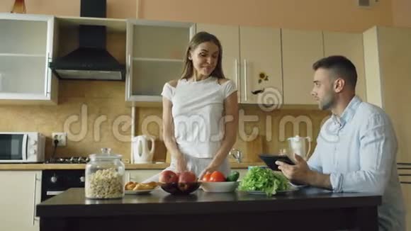 一对漂亮的夫妇一大早就在厨房里聊天帅哥在他女朋友做饭的时候用平板电脑视频的预览图