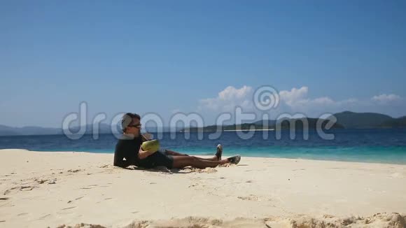 在海滩上喝椰子汁的男人视频的预览图