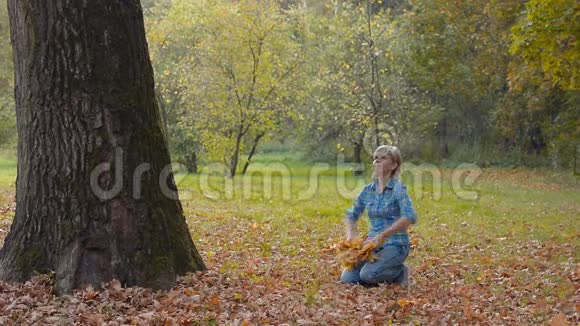 秋天公园的年轻女子举起一臂枫叶视频的预览图