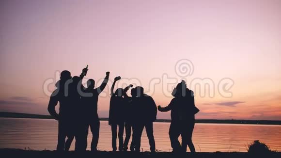 团体青年舞蹈家在日落时在海滩上举行派对视频的预览图
