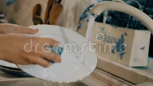 女人正在厨房里用肥皂洗碗带有侧面摄像机运动的特写镜头视频的预览图