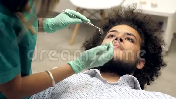 一位女牙医检查年轻人的牙齿视频的预览图